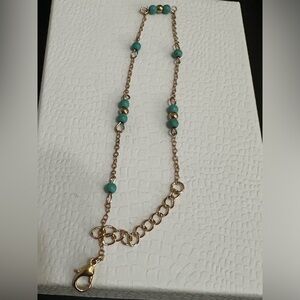 Gold anklet with turquoise beads.